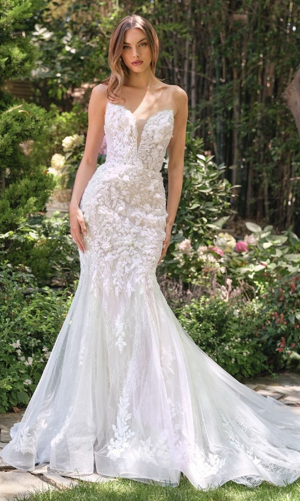 A woman stands outdoors wearing the Andrea & Leo WL088 Strapless Mermaid Bridal Dress, featuring fitted floral lace, a deep sweetheart neckline, and elegant embroidery.